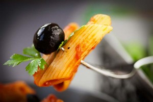 A fork with some pasta and an olive on it