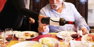 A man pouring wine into a glass at a table.