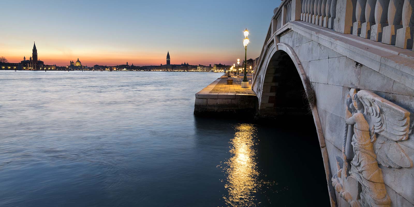 A bridge over the water at night with lights.