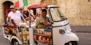 A man driving an open vehicle with people in it.