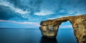 A rock sitting in the middle of an ocean.