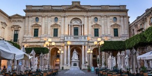 A large building with statues and lights on the outside.