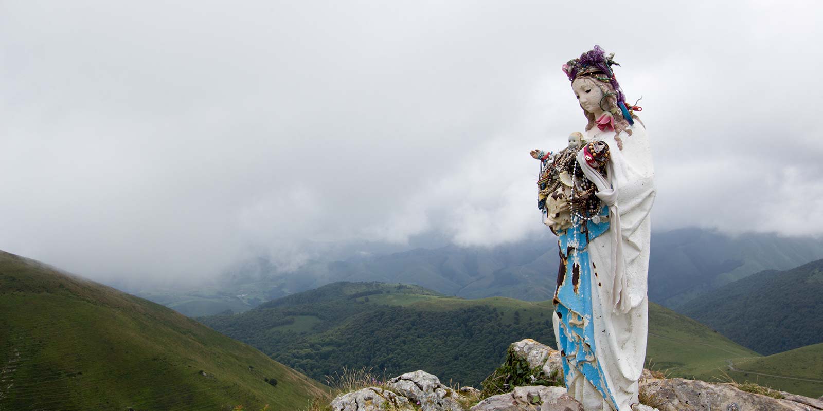 A statue of a woman in front of mountains.