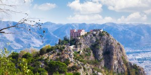 A castle on top of a mountain with trees in the foreground.