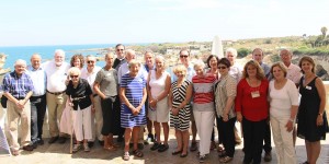 A group of people standing in front of the ocean.