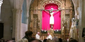 A group of people sitting around in front of a cross.