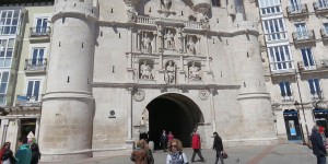 A group of people walking in front of an arch.