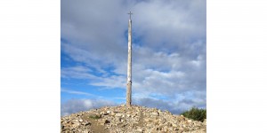 A cross on top of a hill with clouds in the background.