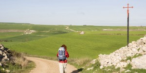 A person with a backpack walking on the side of a road.