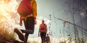 Three people walking in a field with backpacks