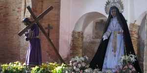 A woman holding a cross in front of flowers.