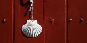 A shell hanging on the side of a red door.