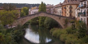 A bridge over water with buildings in the background.