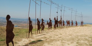 A group of people on horseback are standing in the sand.