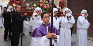 Maltese citizens as they parade through the streets with the Stations of the Cross, some dress in ceremonial robes.