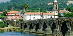 A bridge with arches over the water in front of buildings.