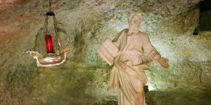 A statue of jesus is in the middle of an underground cave.
