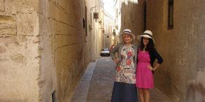 Two women standing in a narrow alley way.