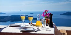 A table with wine glasses and a pitcher of flowers.