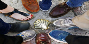 Feet of the Medseas group encircling a shell embedded in the Camino path.