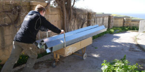 Student working during the Medseas Malta Mission trip pushing a cart loaded with aluminum flashing.